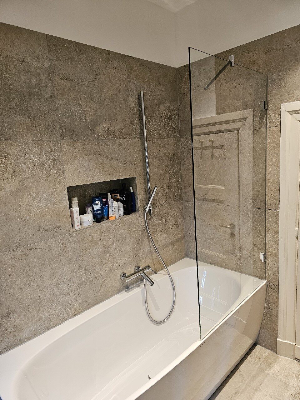 Modern Badezimmer mit weißer Badewanne, grauen Fliesenwänden und Duscharmatur